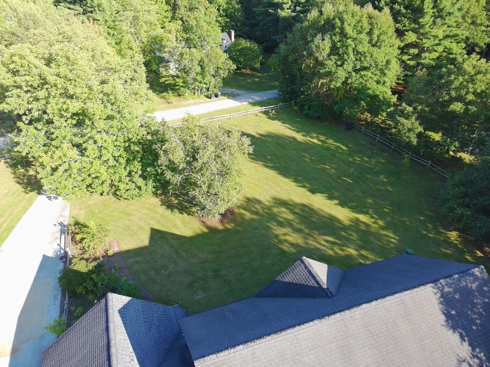 Drone view of a home's exterior siding, roof, and driveway